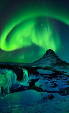 the aurora bore is seen over an icy mountain and waterfall in iceland's faroen