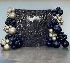 some black and gold balloons are in front of a wall