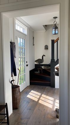 an open door leading into a white room with wood floors and stairs in the background