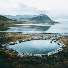 a person sitting in the middle of a lake surrounded by mountains