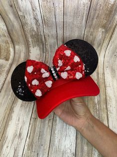 a person holding up a minnie mouse hat with sequins and bows on it