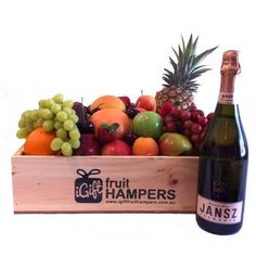 a wooden crate filled with lots of fruit next to a bottle of wine