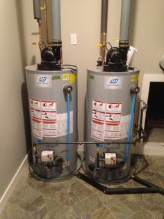 two water heaters sitting next to each other in a room with tile flooring