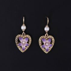 Antique Violet Heart Earrings: Adorn yourself with the charming elegance of these earrings featuring purple enamel violets nestled within hearts of pearls, all set in gleaming 14k gold. Transformed from an antique pin dating back to 1910-1920, they now boast gold ear wires and pearl surmounts, exuding timeless sophistication and vintage allure. Each earring measures 1 inch from the top of the ear wire to bottom by 0.4 inches wide and are in great condition. Upon purchase, your earrings will arrive elegantly packaged, ready for gifting or as a special treat for yourself.  We carefully wrap each piece to ensure a delightful unboxing experience. We also offer free and flexible layaway plans, so take advantage of this option to make owning your dream piece even more achievable. + Trademark Ant Violet Heart, Antique Pins, The Ear, Antique Shops, Heart Earrings, Jewelry Findings, Antique Jewelry, Ring Earrings, Charm Necklace