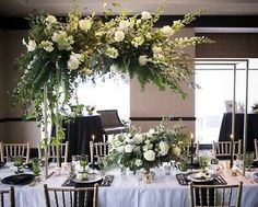 the table is set with black and white linens, gold chairs, and tall centerpieces