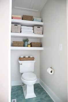 a white toilet sitting in a bathroom next to a shelf filled with towels and other items