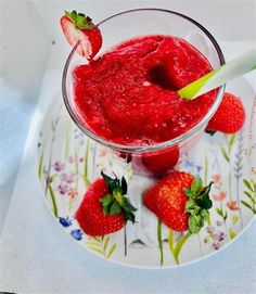 there is a small glass bowl with strawberries in it and a spoon on the side