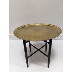 a brass tray with black legs on a white background