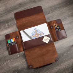 a brown leather case with pens, pencils and notepad