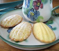 three cookies on a plate next to a tea pot