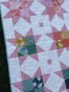 a pink and white quilt is laying on the grass