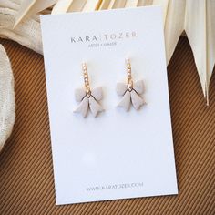 Our trendy bow dangles are oh so adorable and perfect for any time of year. These are handcrafted from clay and feature dainty pearl accent posts that will complement any outfit. COLOR: SPECKLED OATMEAL. Size: Approximately 1 inch from top of posts to bottom. THE DETAILS -Earrings are finished with gold plated faux pearl posts and include rubber backings -Shipped via USPS with tracking *Every pair is uniquely made and slight variations may occur during the creative process. Earrings Handmade Clay, Dangle Pearl Earrings, Pearl Earrings Handmade, Trendy Bows, Pearl Bow, Bow Accessories, Bow Earrings, Pearl Earrings Dangle, Gold Sparkle