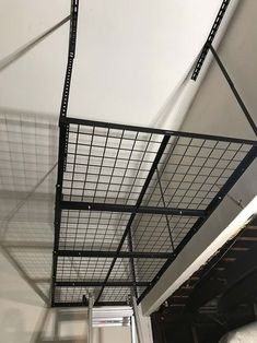 a metal cage hanging from the ceiling in a room with white walls and flooring