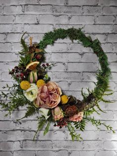 a floral wreath on a brick wall with greenery and flowers in the shape of a circle