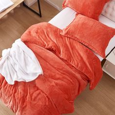 an orange comforter and pillows on a bed