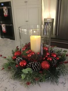 a candle is lit in a centerpiece with pine cones and red balls on it