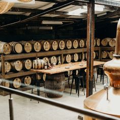 several wooden barrels are lined up in a room with tables and stools around them