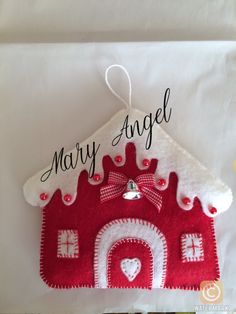 a red and white house ornament hanging from a string with the words mary angel on it