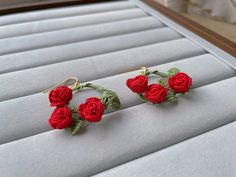 two red roses are attached to gold earwires