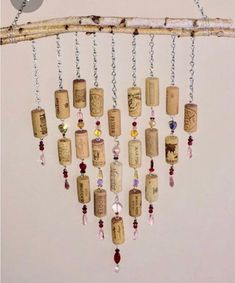 a bunch of wine corks hanging from a tree branch with beads and chains attached to them