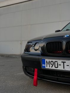 a black bmw is parked in front of a building with a red cone on the ground