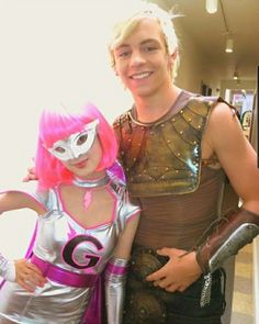 a man and woman in costume posing for a photo together with pink hair, silver bodysuits