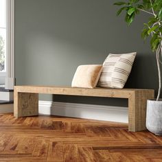 a wooden bench sitting on top of a hard wood floor next to a potted plant