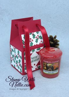 a red candle sitting next to a christmas bag