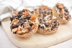 three cupcakes with chocolate chips and nuts on a cutting board next to a fork