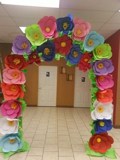 an arch made out of paper flowers in a hallway