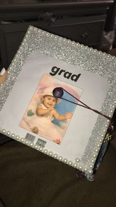 a photo frame with the word grad on it and beads around it, sitting on a chair