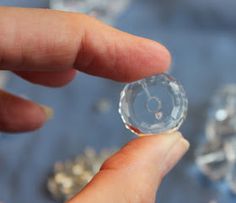 a hand holding a crystal ball in front of some other glass objects on a table