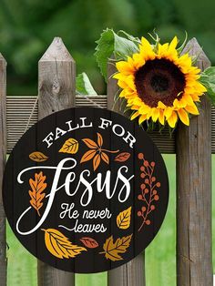 a wooden fence with a sunflower on it and a sign that says, fall for jesus he never leaves