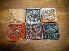 four square coasters with designs on them sitting on top of a wooden table next to each other