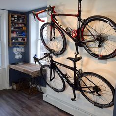 a bicycle mounted to the side of a wall with two bikes hanging from it's sides