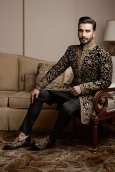 a man sitting on top of a couch in a living room next to a chair