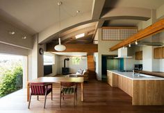 an open kitchen and dining area with wood flooring in a modern style home on the outskirts of trees