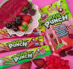 some fruit and candy are on a pink surface