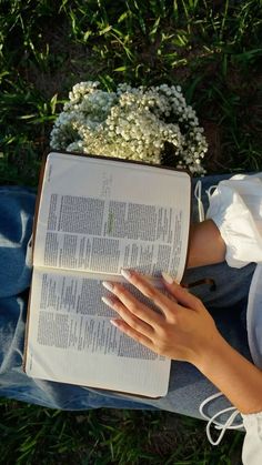 a person laying on the ground reading a book with flowers in it and holding an open book