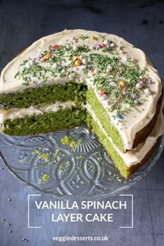 a green cake with white frosting and sprinkles on top is cut in half