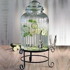 a glass jar filled with cucumbers and water on top of a metal stand