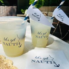 two cups with straws sitting on top of a table next to paper signs that say let's get nautity