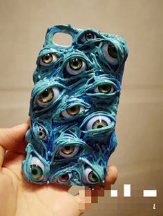 a hand holding up a cell phone case with eyeballs on it