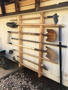 there are many tools hanging on the side of this shed, including shovels and rakes