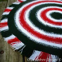 a red, white and black rug with fringes on top of wooden flooring