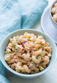 two bowls filled with macaroni salad on top of a white countertop next to a blue towel