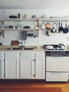 a white stove top oven sitting inside of a kitchen next to a wooden countertop