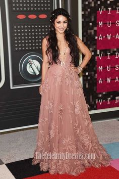 a woman in a pink dress standing on a red carpet with her hands on her hips