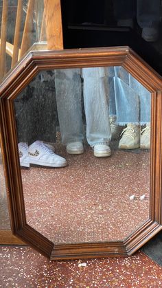 a mirror that is on the ground with shoes in front of it and someone's feet