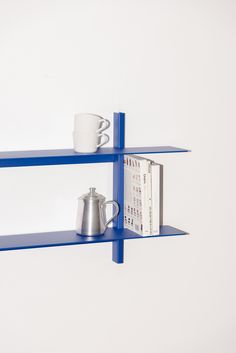 two blue shelves with cups and books on them